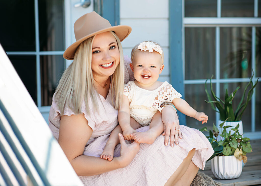 mommy and me photography session with mom wearing a tan colored rim hat and baby in cream lace dress