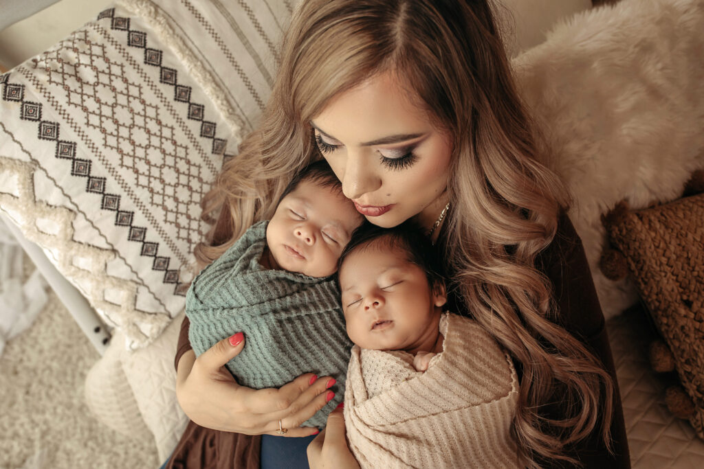 mom with beautiful hair and make up holding twin newborns
