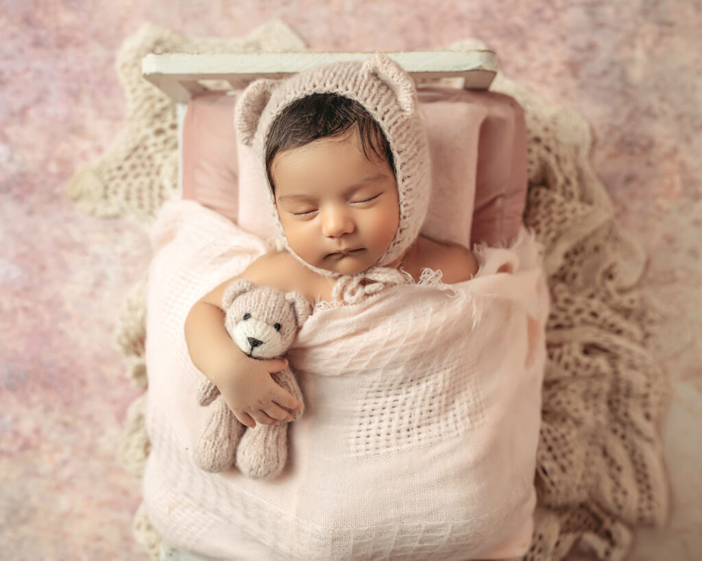 Newborn baby girl in newborn sized bed. Styled newborn session in Oklahoma City