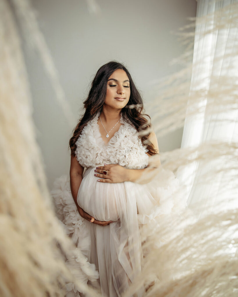 maternity photo with cream colored dress with professional hair and makeup