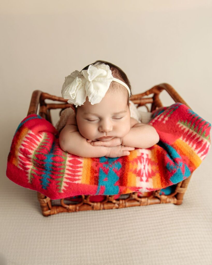 baby on colorful blanket with big white bow