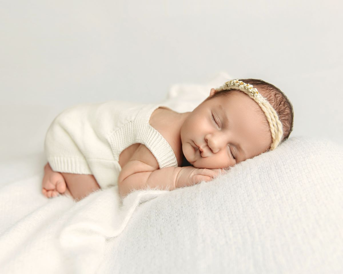sleeping baby in white outfit during their newborn photography session