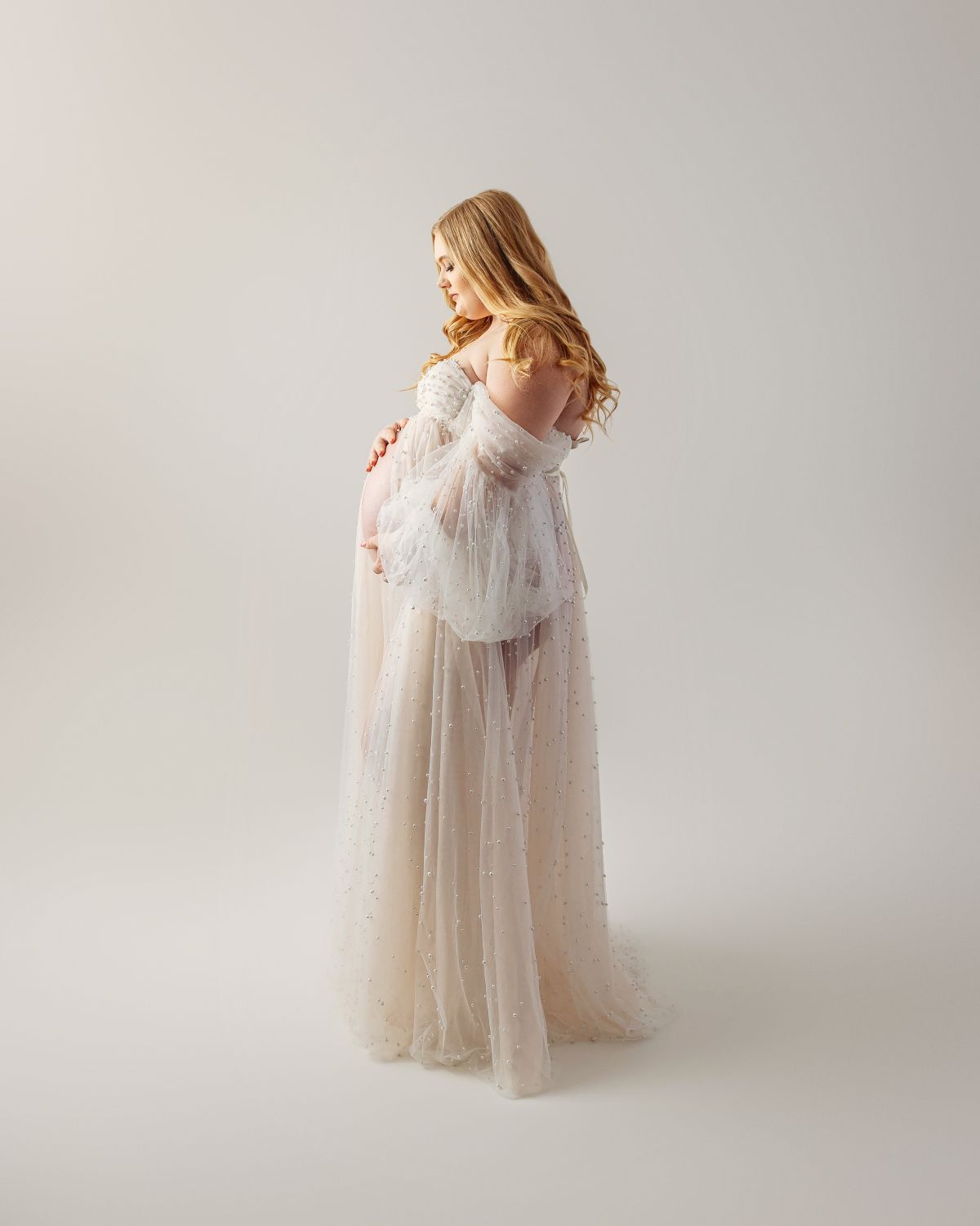 mother in maternity photoshoot wearing a white gown 
