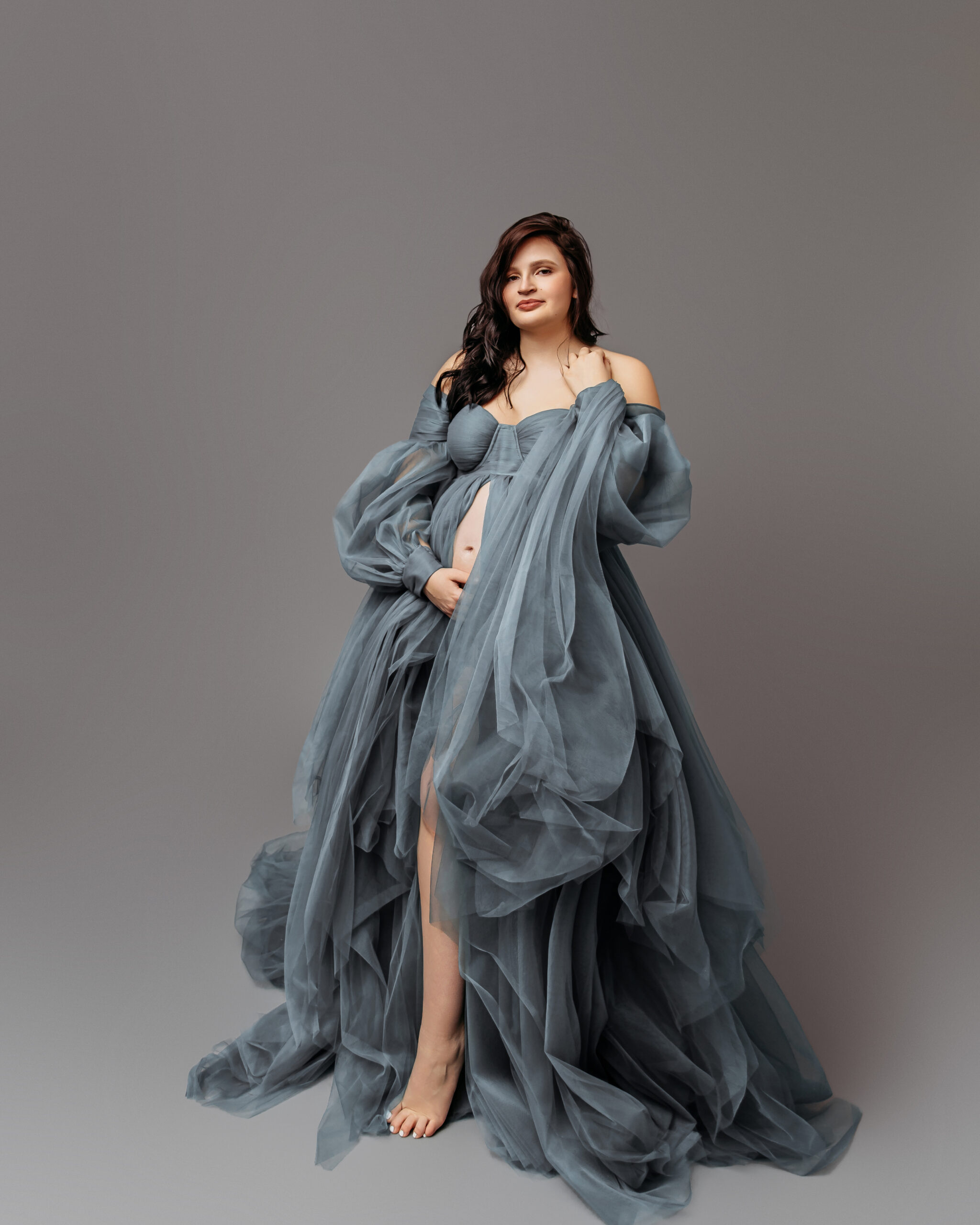mother in grey flowy maternity outfit posing