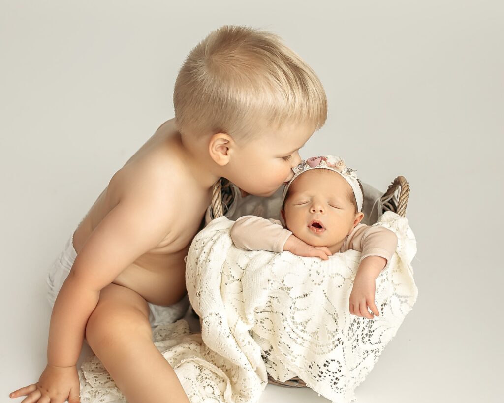 Big sibling sharing a sweet moment with newborn during newborn photography session
