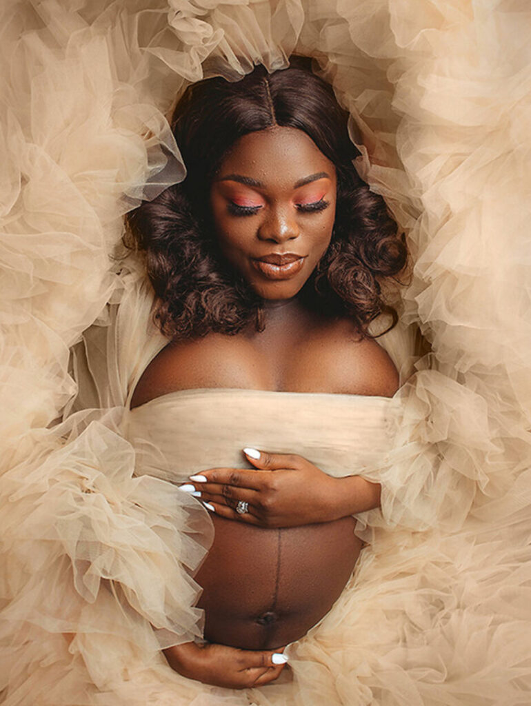 mother laying with beige gown in maternity session