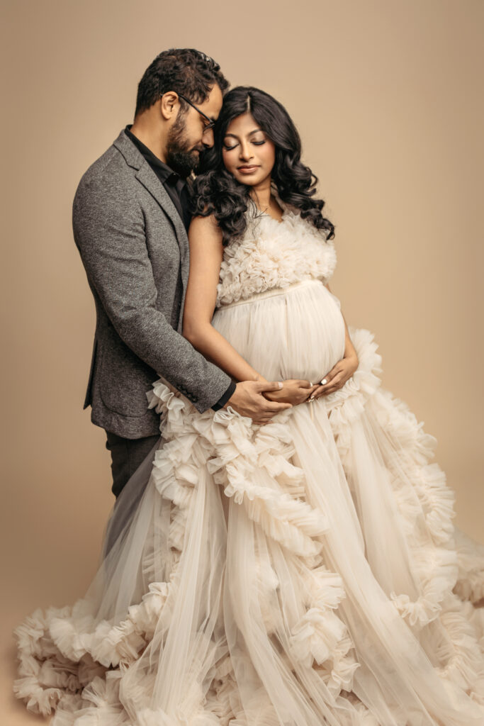 mama in white gown holding bump with partner behind her