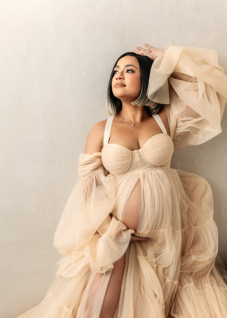 Indoor studio maternity portrait with mom wearing flowy vanilla colored dress.