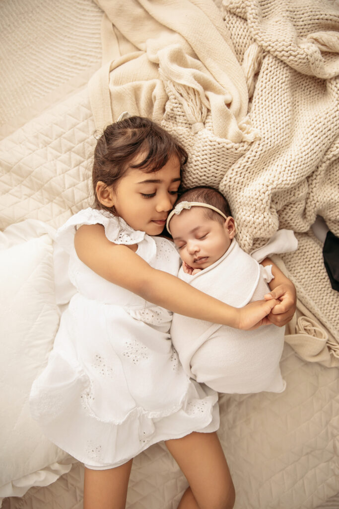A big sister gently smiling at her sibling during a calm, stress-free studio session with a premier newborn photographer in OKC.