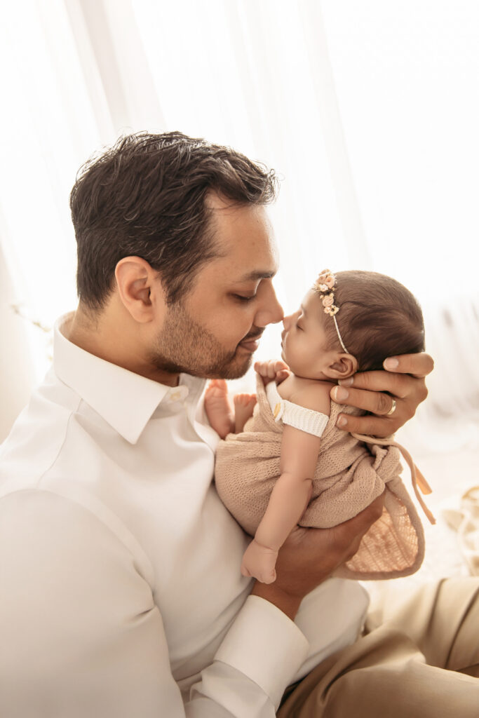 A proud dad holding his baby in a climate-controlled studio for summer newborn photos by Oklahoma City photographer Ashley McClintock Photography.