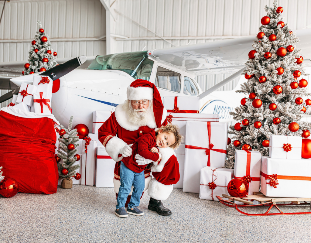 Little boy in red with Santa posing for Christmas mini session photos.