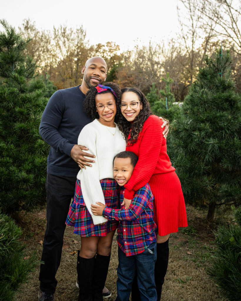 Family taking holiday photos on a tree farm with coordinating outfits.