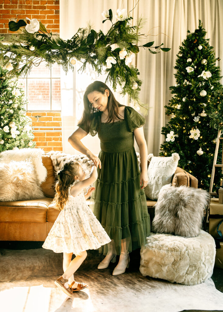 Mom smiling while she spins daughter during Christmas family photos.