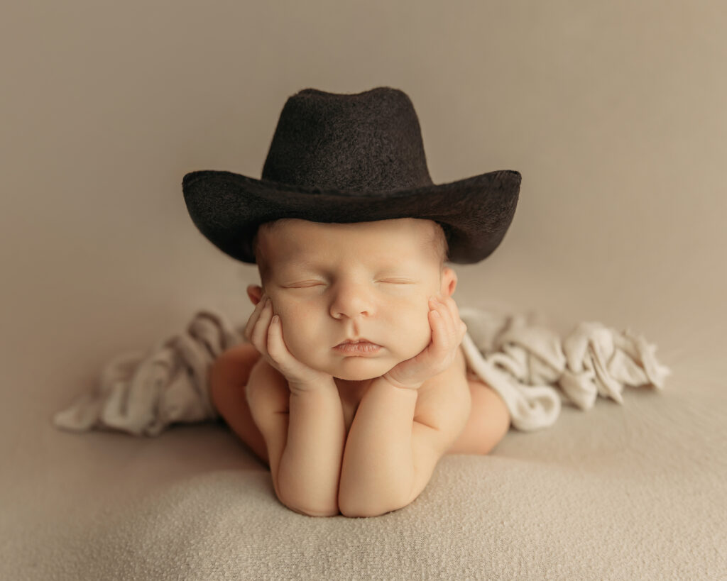 Newborn pictures with a miniature cowboy hat.